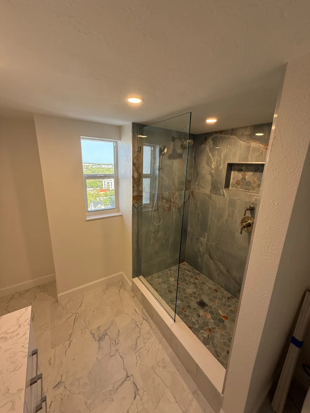 Walk-in shower with a glass panel and large-format tile